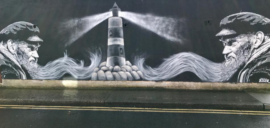 Beautiful, black and white graffiti with the men, near the lighthouse among the stones