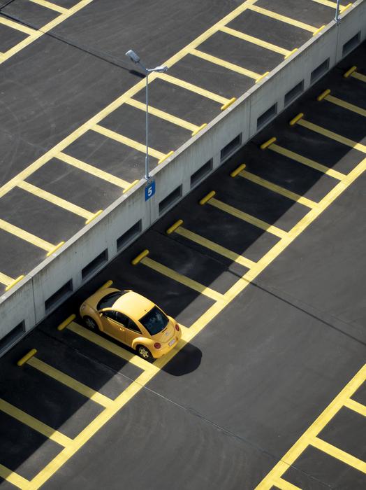 Yellow car on the parking lot in shadow and sunlight, on Lijnbaan in Rotterdam, Netherlands