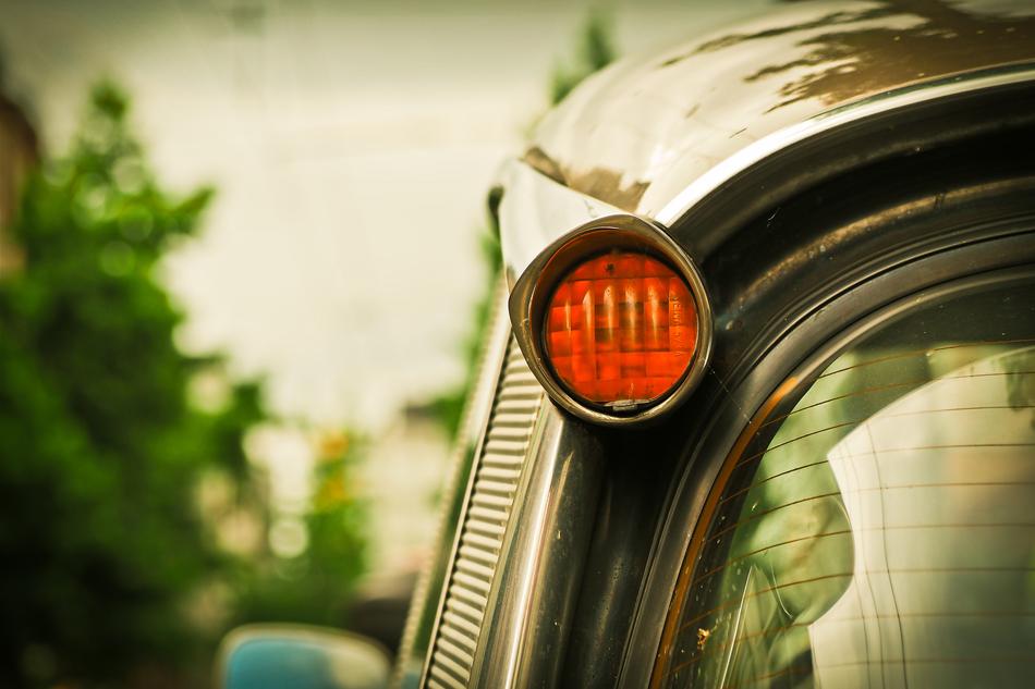 Close-up of the blinker of the shiny 'Citroen DS' car, near the green plants