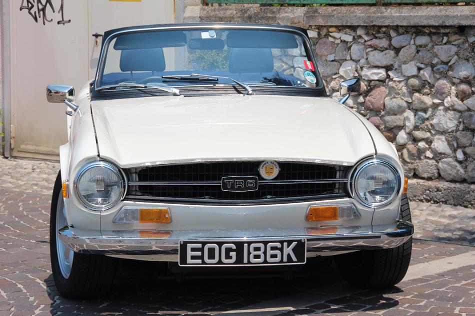 Front view of the old, beautiful, white oldtimer car near the wall