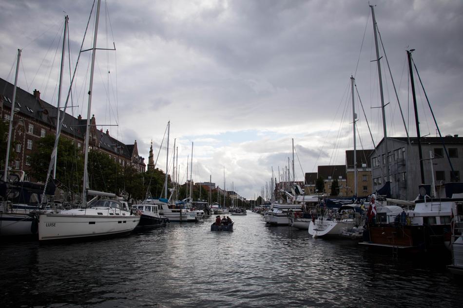 Cityscape of the beautiful port with ships, among the buildings, under the blue sky with grey clouds