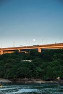 full moon over road bridge across river at dusk