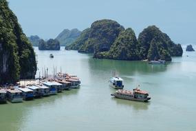 Boats on green calm water at scenic forested Rocks