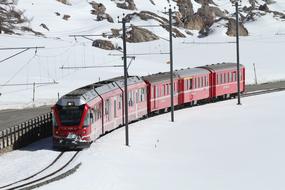 red passenger Train at snowy mountains, switzerland