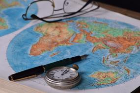 pen, watch and glasses lie on the world map