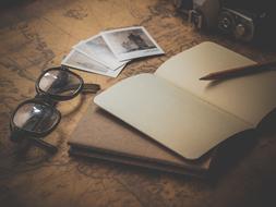 open notebook, vintage glasses and old postcards on the table