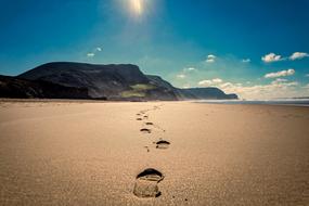 footprints of man on sand by the ocean