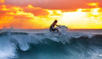 Surfer at top of foamy high Wave at Sunset, indonesia, java