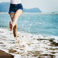 Barefoot woman, doing water splashes on the sandy beach
