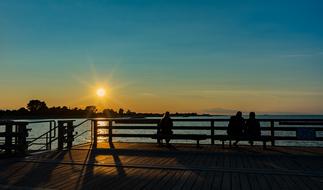 people resting on benches looking at scenic Sunset