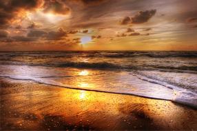 sunset in the clouds over the sandy sea beach