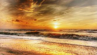 Beautiful, shiny beach of the North Sea, with the waves, at colorful and beautiful sunset