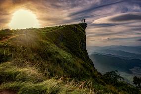 silhouettes of people on a green cliff in Thailand