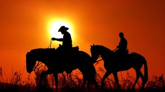 two Riders Silhouettes at sunset sky