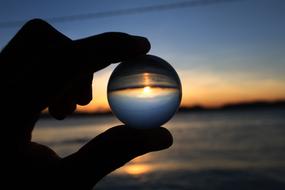 glass ball in hand on sunset background