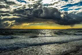 waves on the shore near the sea under cumulus clouds