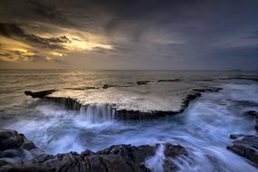 scenic Cascades and tides on coastline rock formations at dusk