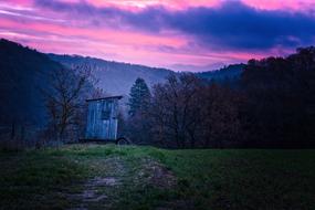 weathered cabin near forested mountains at Twilight on the beautiful colorful landscape