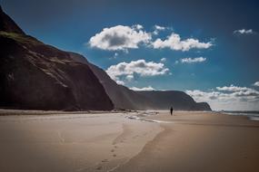 lonely man walks along the sandy beach of the ocean