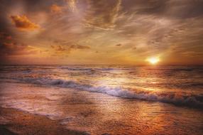 Beautiful and colorful beach of the North Sea, with the waves, at colorful and beautiful sunset in the sky, with the clouds, in Denmark