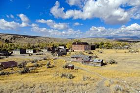 Old Bannack Townsite on the colorful hills in Montana, America, under the blue sky with clouds