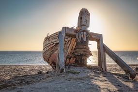 Vintage boat with the winch, on the sandy beach, in sunlight, at colorful sunset