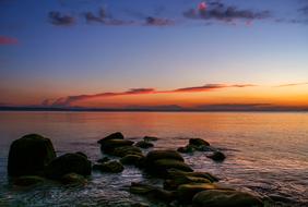 Beautiful landscape of the rocky coast, at colorful, gradient afterglow in the sky with clouds