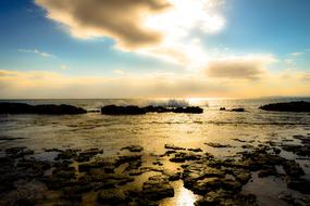 sea waves are hitting stones on the shore against the backdrop of sunset