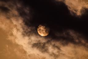 the moon in the sky behind the clouds at dusk