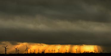 rain clouds over silhouettes of wind turbines