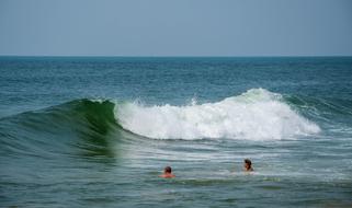 people swim in the ocean among high waves