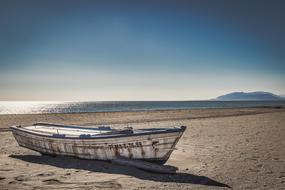 weathered empty Boat on sand beach at glossy sea