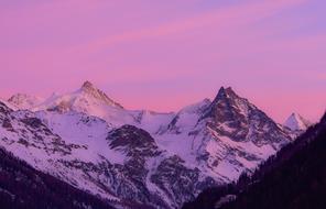 photo of snowy mountains in the village of Zinal on a background of purple sunset