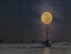 power lines against the background of the night sky and the full moon