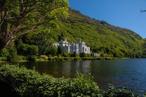 Beautiful landscape with the castle on the green shore with mountains, near the lake in Ireland, UK