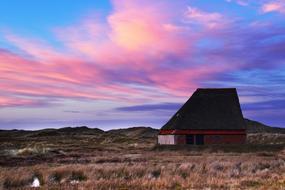 Beautiful house among the colorful field on landscape at colorful sunset