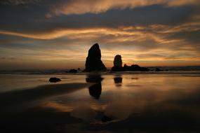 silhouettes of boulders on the coast at dusk