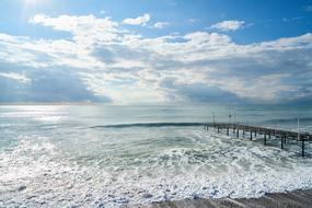 long wooden pier on calm glossy sea