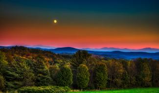 green forest against a colorful sky and full moon in Vermont