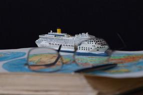 Cruise ship, glasses and pen on the colorful World map