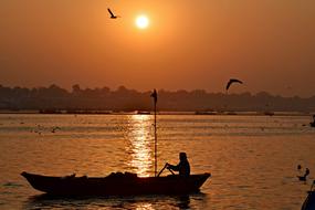 photo of a fisherman in a boat on a background of golden sunset