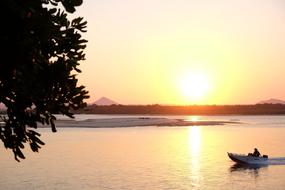 People on the boat, at colorful and beautiful sunset and mountain on background