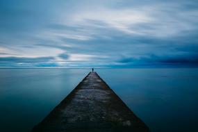 lonely silhouette on a long pier at dusk