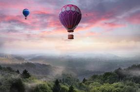 hot air balloons high above misty mountains amid romantic sunset