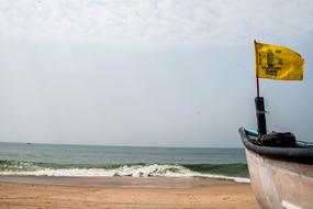 boat with a yellow flag on the seashore