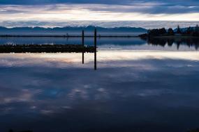 Beautiful waterscape of the ocean, with the pier, at colorful sunset and mountains on background
