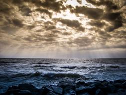 sunbeams bursting through Clouds to dark stormy sea