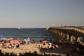 people relax on the beach near the pier in summer