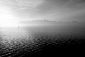 black and white photo of a sailing ship far into the sea