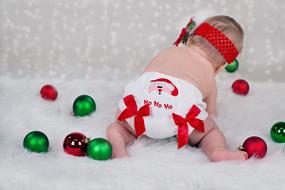 Cute baby in the colorful, cute Christmas clothing, among the colorful and beautiful Christmas decorations